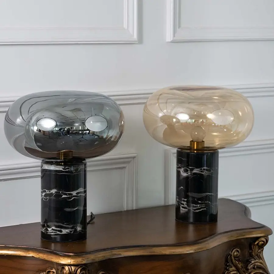 Collection of contemporary smoked glass table lamps with black marble bases on white background showcasing timeless modern elegance.