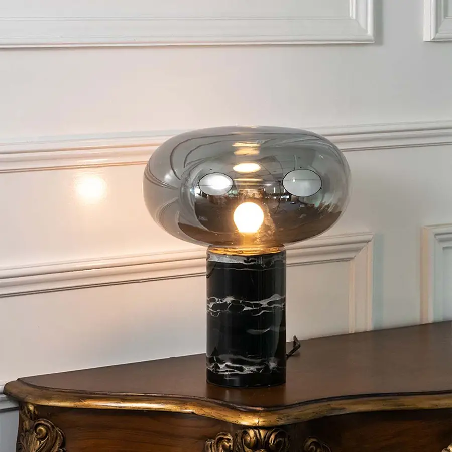 Smoked glass table lamp with black marble base and exposed bulb designed for sophisticated modern table lighting.