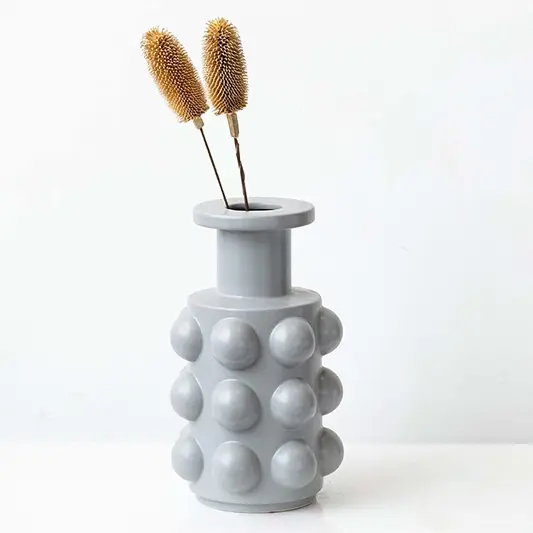 Dried dipsacus thistle stems in a grey bubble vase offering a décor accent perfect for natural boho styling and modern minimalist interior decoration.