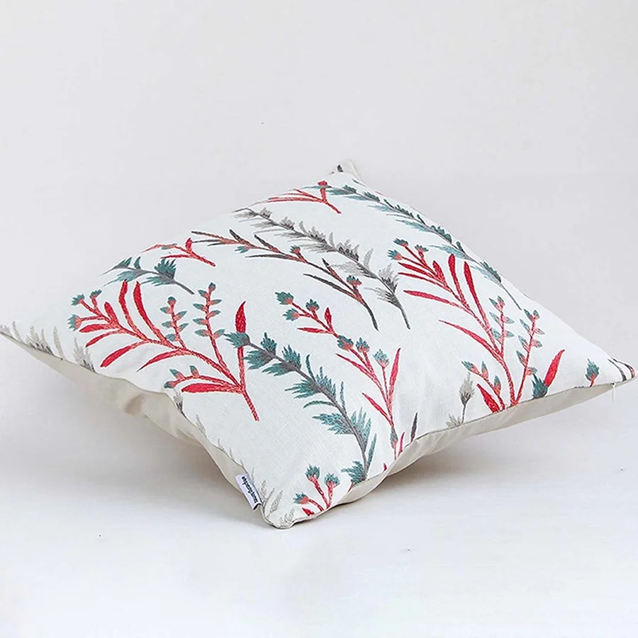 Soft cotton cushion cover with coral and teal botanical design shown at an angle creating a lively nature inspired décor accent with a breathable gentle and skin friendly fabric.