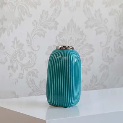 Ribbed blue ceramic vase with glossy finish and silver accent on plain white background.
