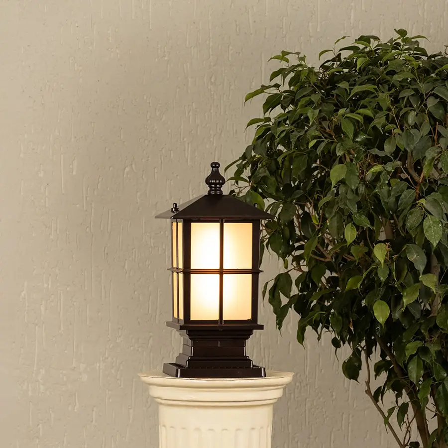 Black outdoor gate light styled beside green plants for elegant modern exterior decor ambiance.