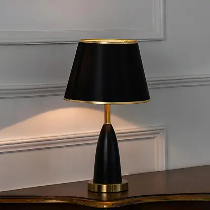 Black metal table lamp with black fabric shade displayed on a wooden console table creating sophisticated ambient lighting.