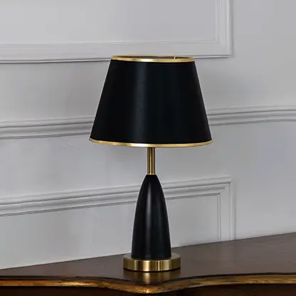Black and gold table lamp with fabric shade turned off against white background elegant bedside decor table lamp.
