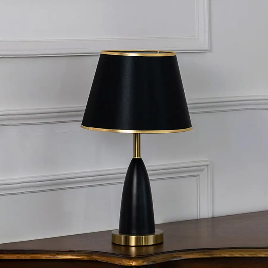 Black and gold table lamp with fabric shade turned off against white background elegant bedside decor table lamp.