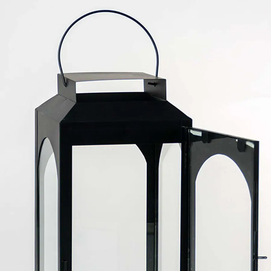 Closeup of black metal lantern with open glass door and hanging loop for tabletop decor styling.