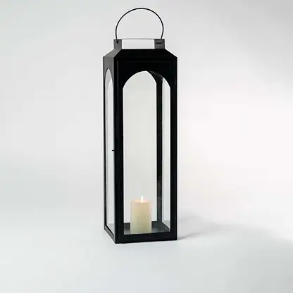 Tall black lantern illuminated softly against a white background showcasing reflective glass and metal sheen.