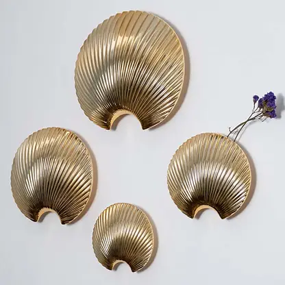 Gold shell wall decor styled with matching metallic pieces creating a cohesive modern wall display for home interiors.