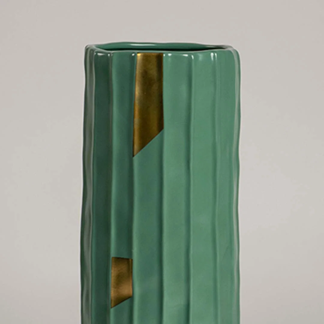 Closeup of green ribbed ceramic vase featuring glossy finish and gold accent details ideal for stylish modern home decor accents.