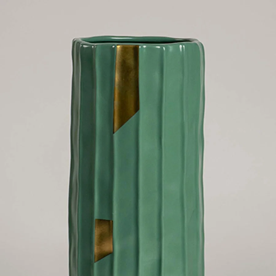 Closeup of green ribbed ceramic vase featuring glossy finish and gold accent details ideal for stylish modern home decor accents.