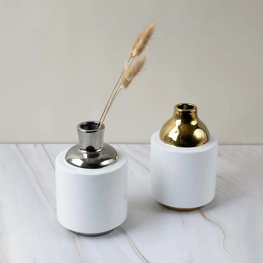 White ceramic decorative vase with gold metal lid placed on tabletop showing smooth finish premium material and elegant accent for modern interiors.
