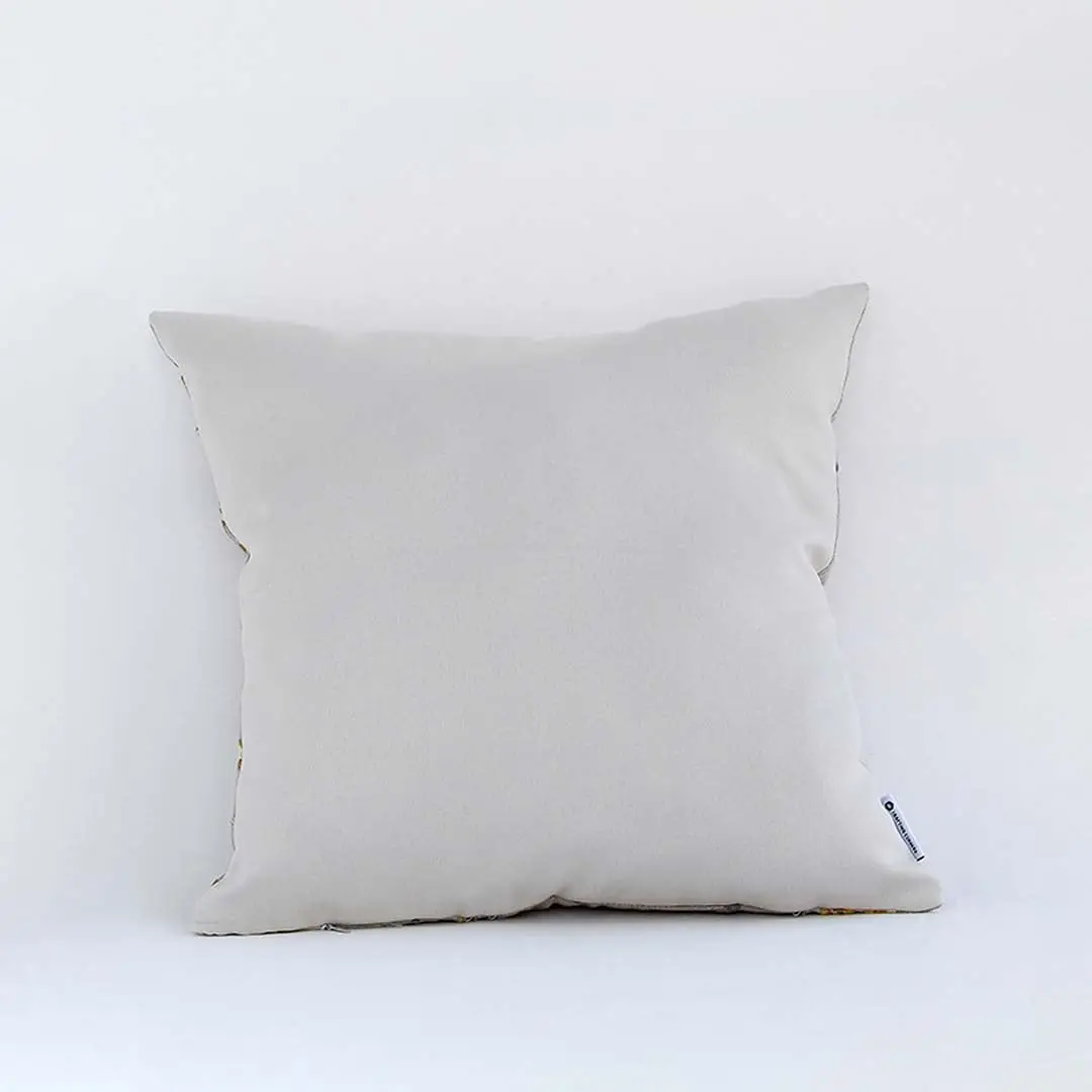 Cream cushion with raised leaf embroidery shown from a soft angled back view highlighting its texture plush form and natural modern decorative appeal.