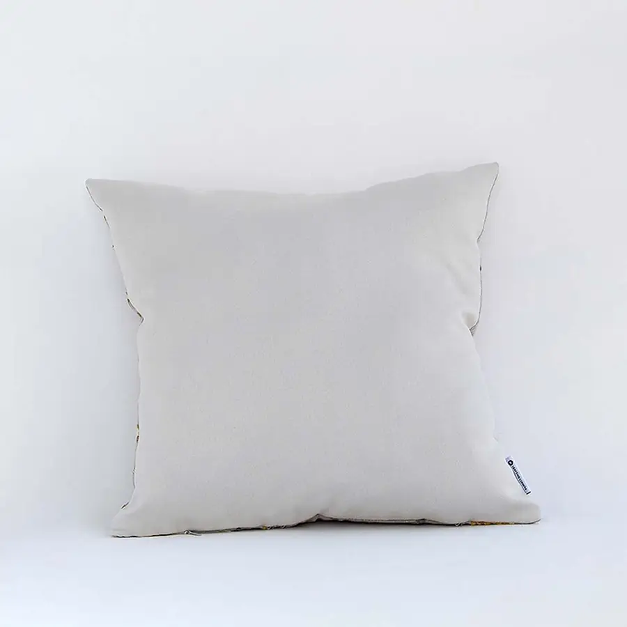 Cream cushion with raised leaf embroidery shown from a soft angled back view highlighting its texture plush form and natural modern decorative appeal.