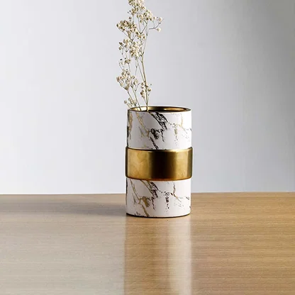 White marble finish metal candle holder with gold accent placed on wooden table adding modern luxury touch to home Decor.