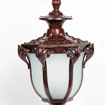 Detailed closeup of outdoor brown metal pillar lamp with frosted glass shade and intricate vintage decorative design.
