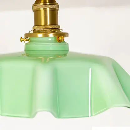 Closeup view of the mint green ruffled ceiling light showing its soft glass texture and gold mount details.