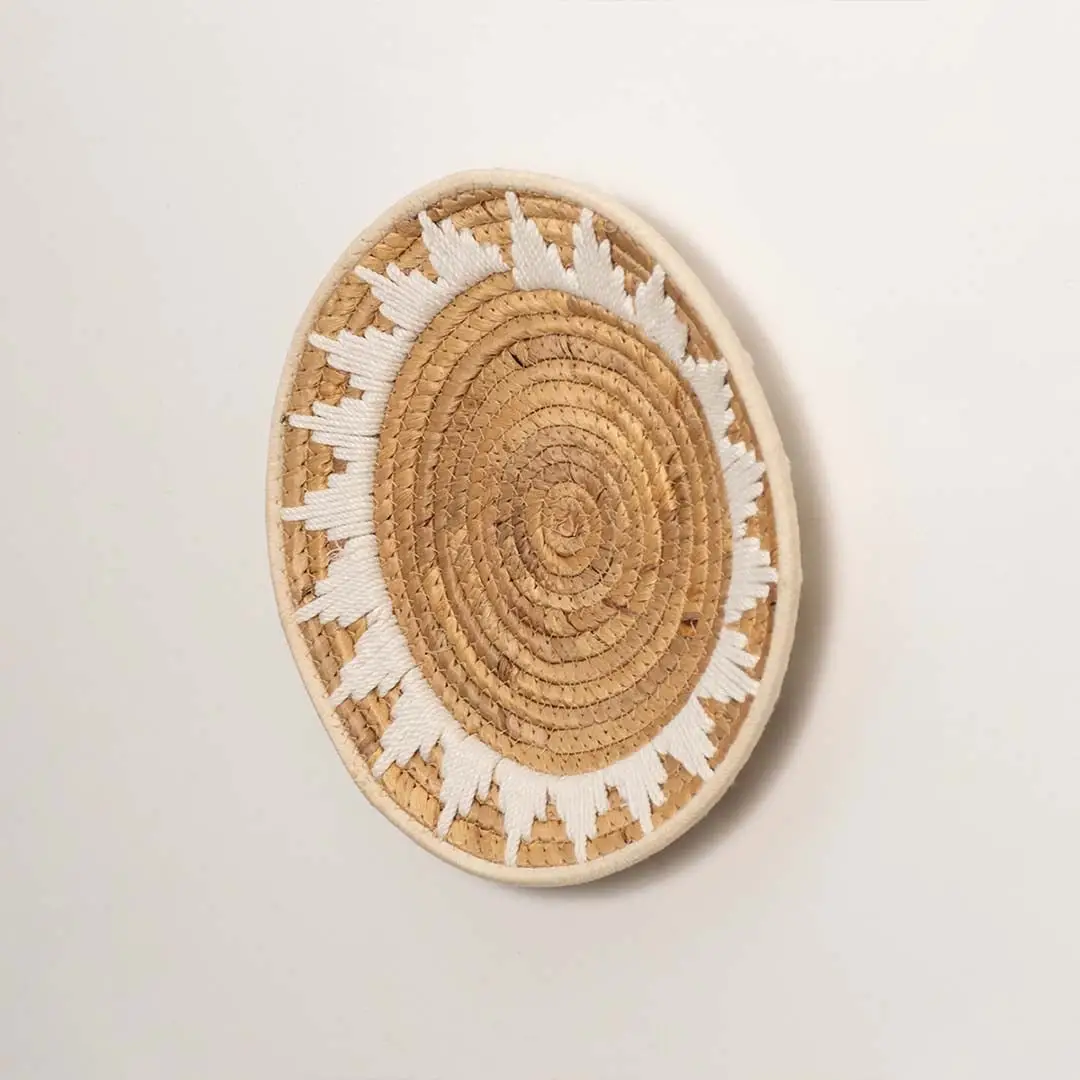 Side profile of the flat woven wall basket showing the thick natural fiber coils and white wrapping details on a white surface.
