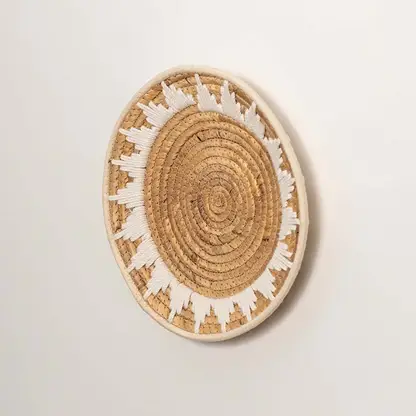 Side profile of the flat woven wall basket showing the thick natural fiber coils and white wrapping details on a white surface.