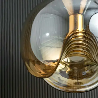 Detailed view of amber glass and brass metal pendant light highlighting premium reflective craftsmanship.
