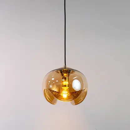 Amber glass and brass metal pendant light with warm illumination for elegant home decor spaces.