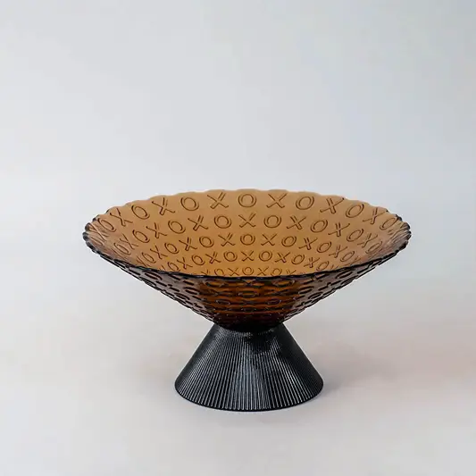Amber glass decorative bowl with black pedestal base for elegant tabletop styling and contemporary home decor.