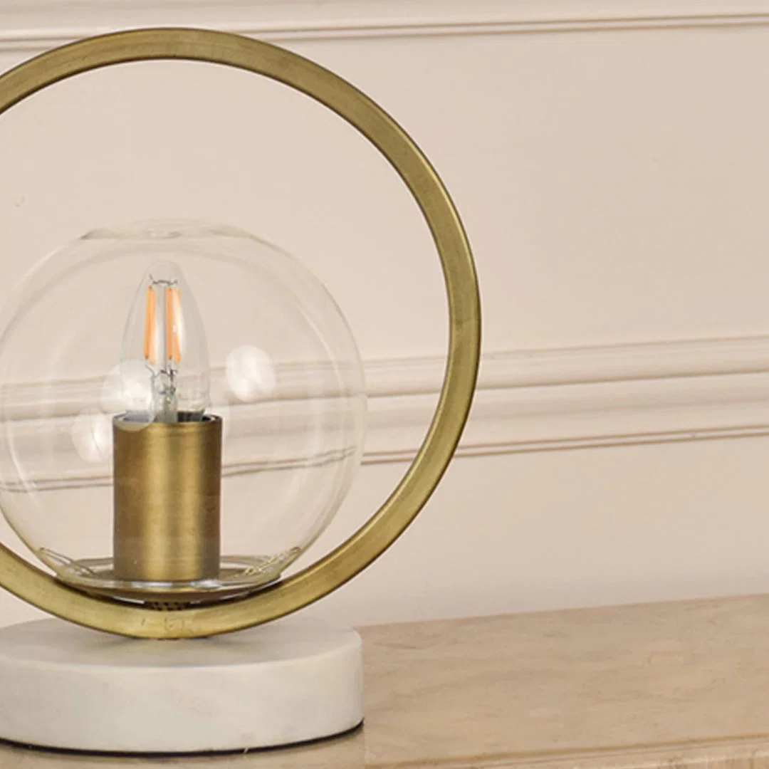 Closeup of gold and glass table lamp showcasing intricate metallic frame and polished marble base crafted for premium interior design.