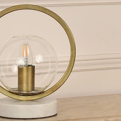 Closeup of gold and glass table lamp showcasing intricate metallic frame and polished marble base crafted for premium interior design.