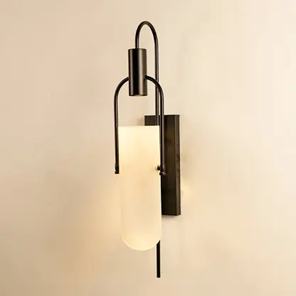 Black metal wall sconce with frosted glass shade glowing softly on white background for ambient lighting.