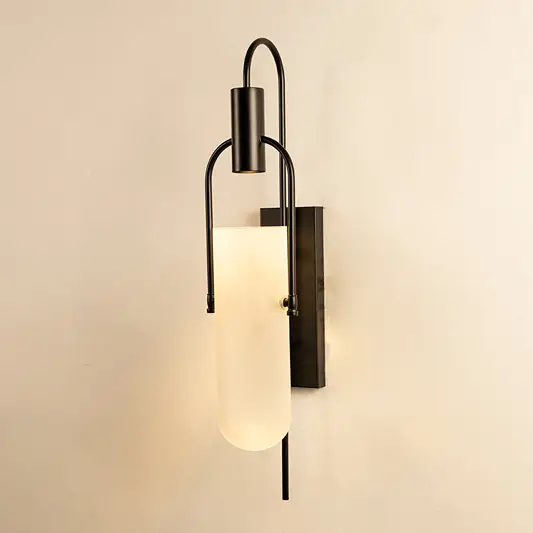 Black metal wall sconce with frosted glass shade glowing softly on white background for ambient lighting.