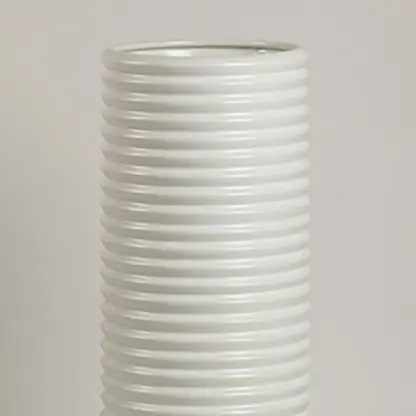 Closeup of white ceramic vase showing ribbed detailing and smooth handcrafted finish for minimalist artistic appeal.