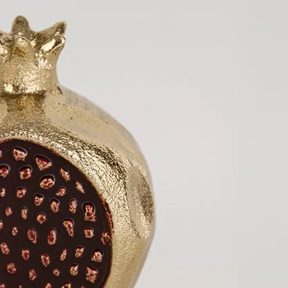 Closeup view of the gold pomegranate decor showing the raised seed pattern and detailed surface texture