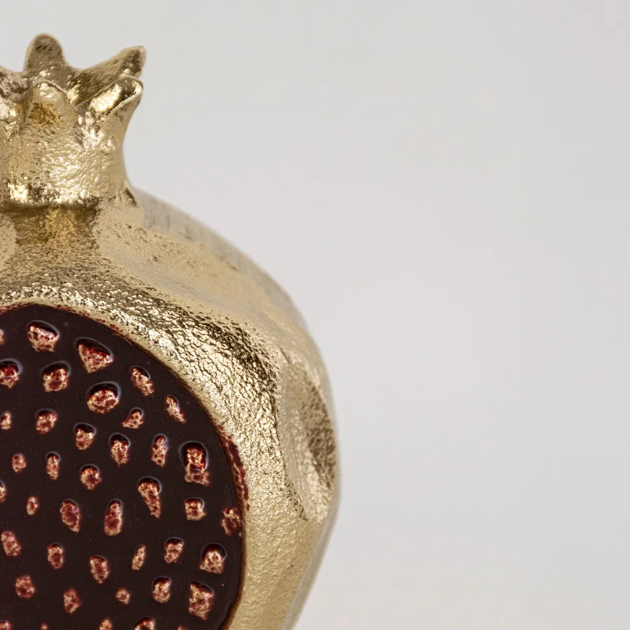 Closeup view of the gold pomegranate decor showing the raised seed pattern and detailed surface texture