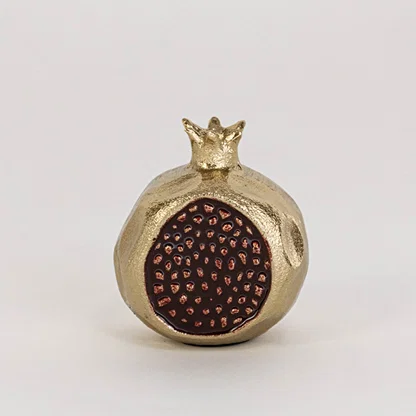 Golden pomegranate decor piece displayed on a clean white background highlighting its textured seed design