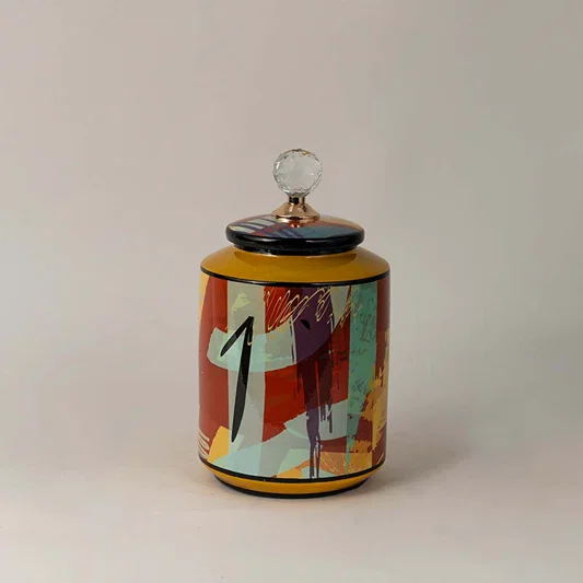 Colorful ceramic jar with cylindrical shape and bright abstract print standing elegantly on a white surface.
