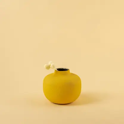 Minimalist matte yellow round metal bud vase with dried stem for modern home decor and elegant shelf accents.