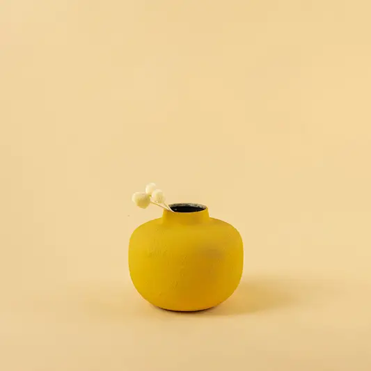 Minimalist matte yellow round metal bud vase with dried stem for modern home decor and elegant shelf accents.