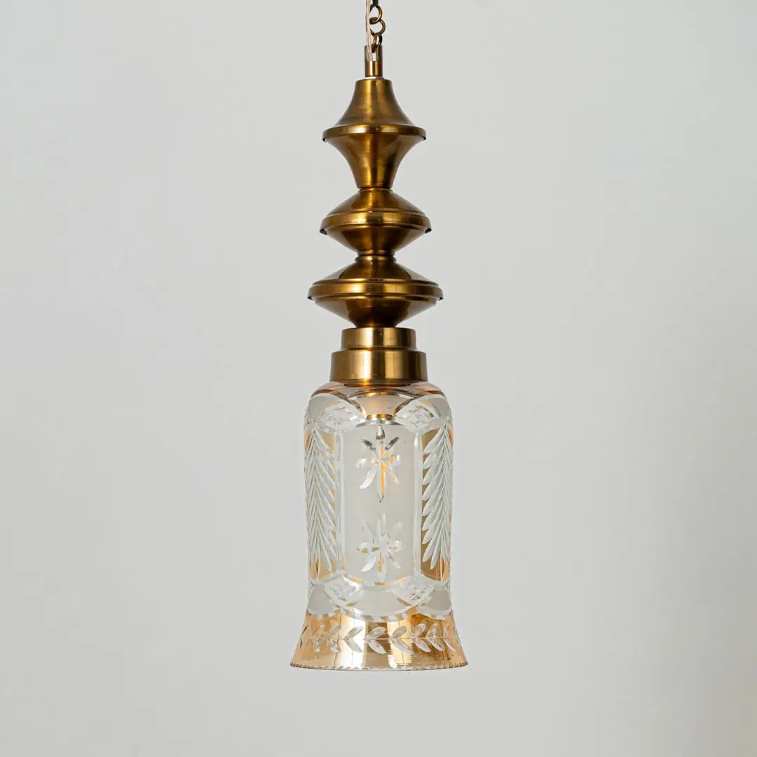 Patterned glass and gold metal pendant light with decorative design for timeless interior styling.