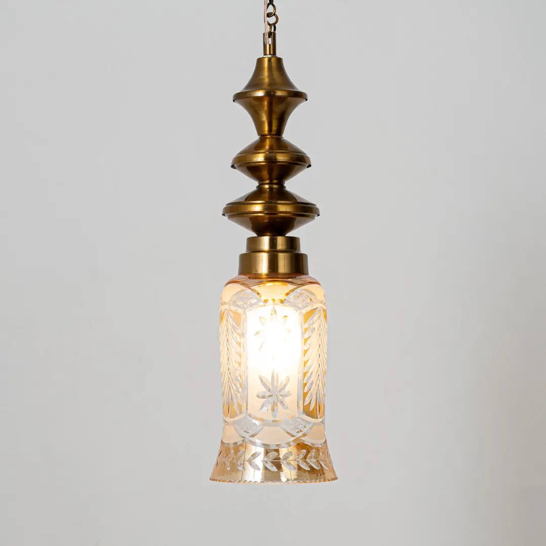 Decorative pendant light in gold metal finish with textured glass shade for dining room or living decor lighting white background.