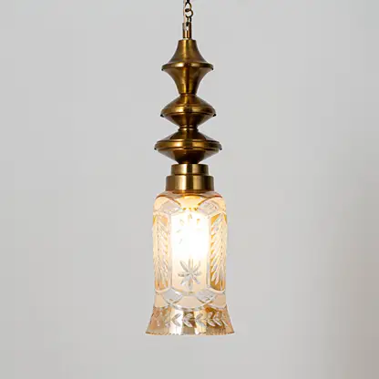 Decorative pendant light in gold metal finish with textured glass shade for dining room or living decor lighting white background.