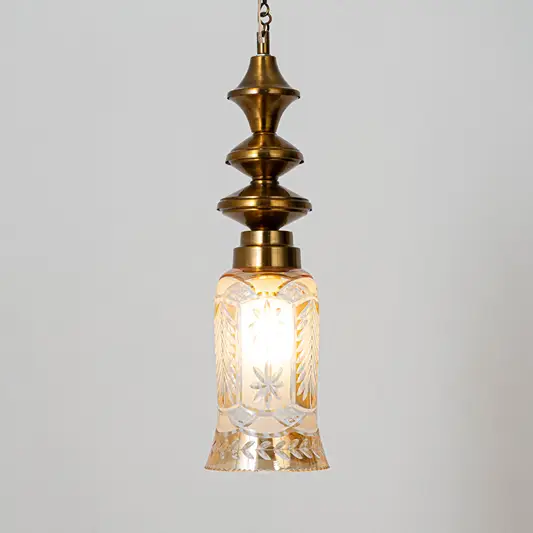 Decorative pendant light in gold metal finish with textured glass shade for dining room or living decor lighting white background.