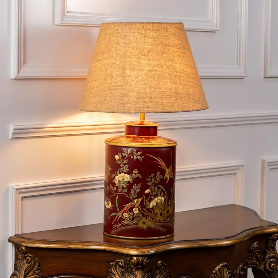 Gilded Phoenix red table lamp on white background with light on showcasing rich pattern warm illumination and artistic interior appeal.