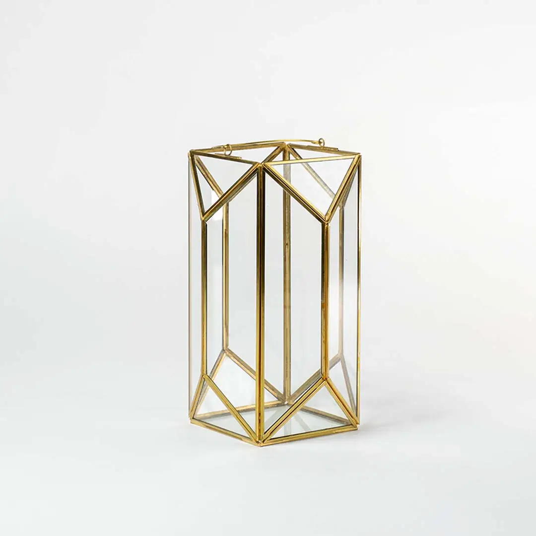 Gold metal geometric candle holder with open frame design for luxury tabletop decor styling use.