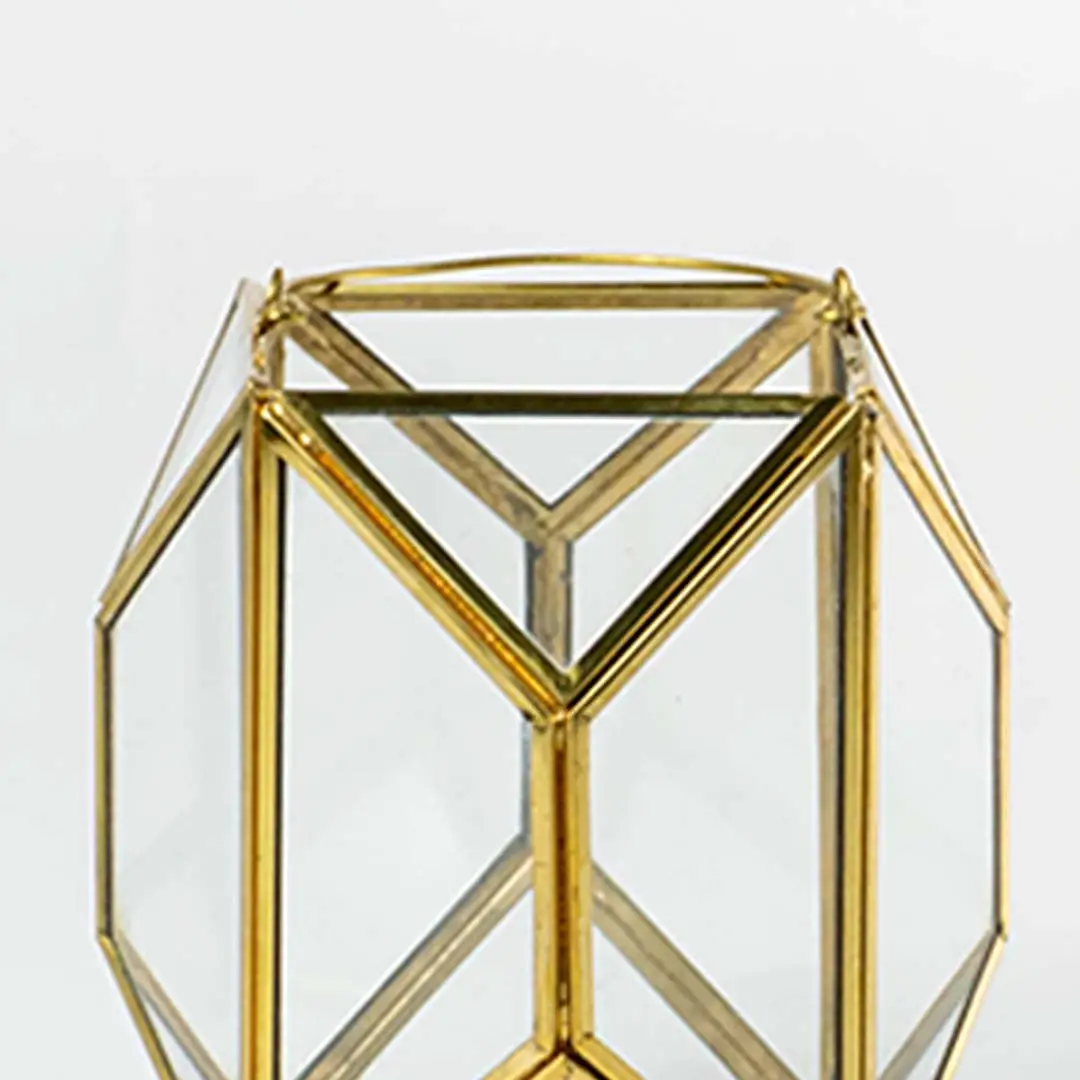 Closeup of gold geometric lantern highlighting refined metal edges and clear glass panels creating a premium modern decorative piece for interiors.