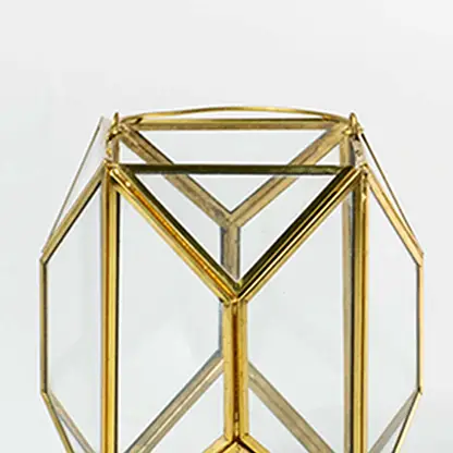 Closeup of gold geometric lantern highlighting refined metal edges and clear glass panels creating a premium modern decorative piece for interiors.