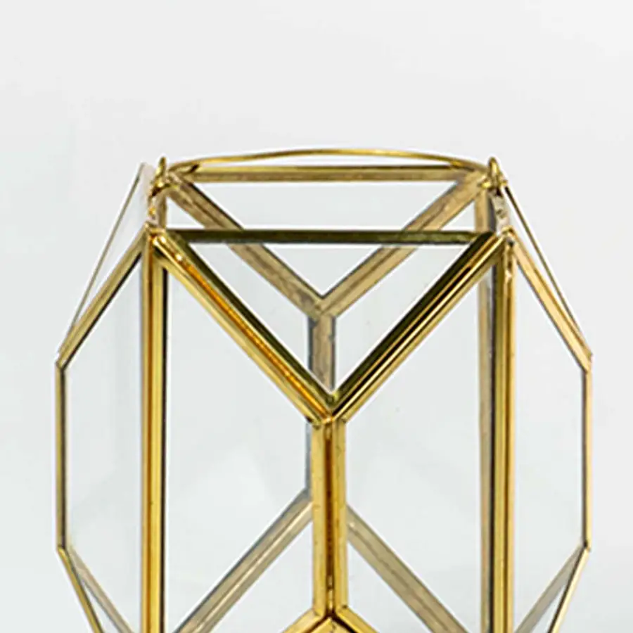 Closeup of gold geometric lantern highlighting refined metal edges and clear glass panels creating a premium modern decorative piece for interiors.
