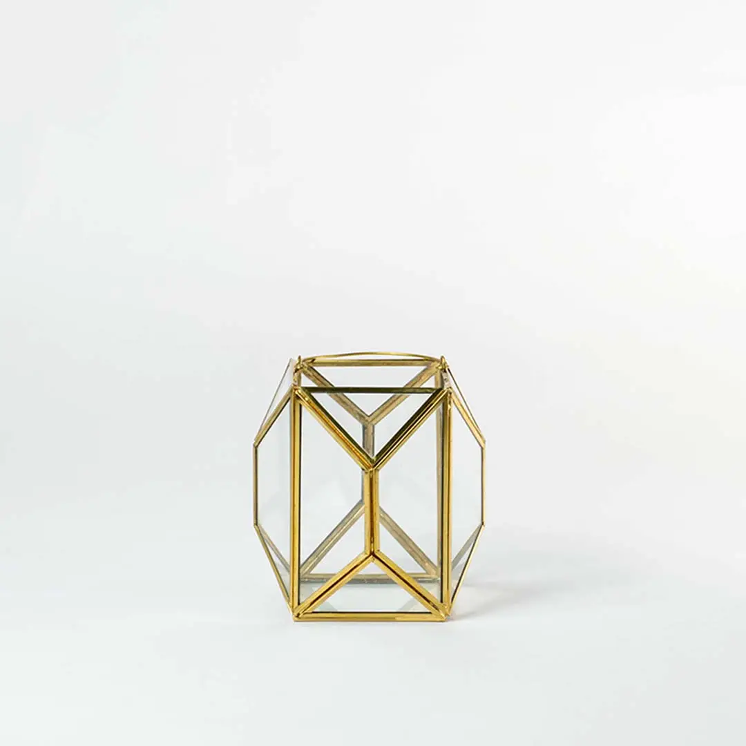 Gold metal geometric candle holder with open frame structure for modern tabletop decor styling.