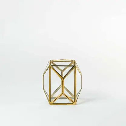 Gold metal geometric candle holder with open frame structure for modern tabletop decor styling.