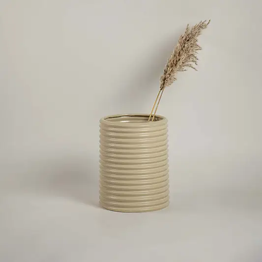 Contemporary beige ceramic vase with ribbed design styled with dried flowers for elegant living space decoration.