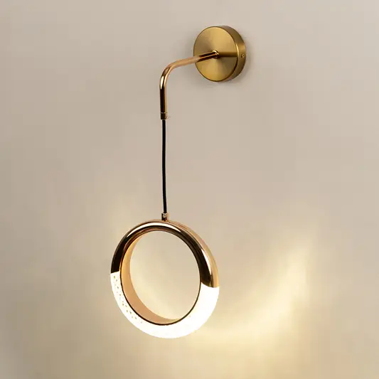 Modern brass ring wall light with warm halo glow for elegant bedroom and hallway interior decor.