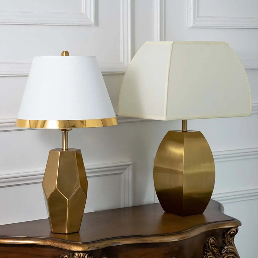 Gold faceted table lamps with white tapered shades shown together with lights off highlighting elegant geometric bases for modern home styling.